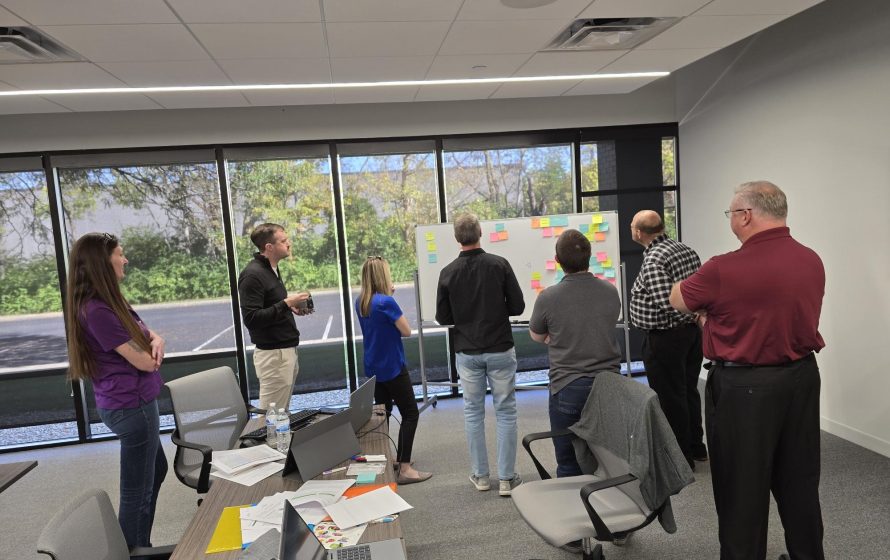 Group of people looking at whiteboard with post it notes