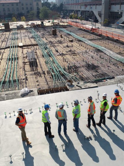 Apogee employees in safety gear standing on a construction site