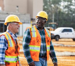 Construction workers in safety gear walking and talking on construction site