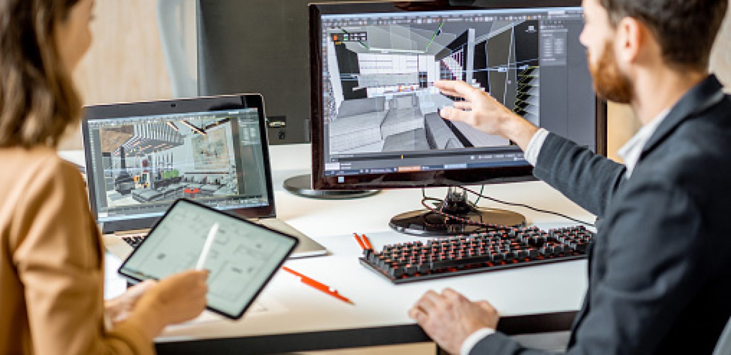 Two creative office employees making interior design on the computer and digital tablet at the modern office of architectural firm.