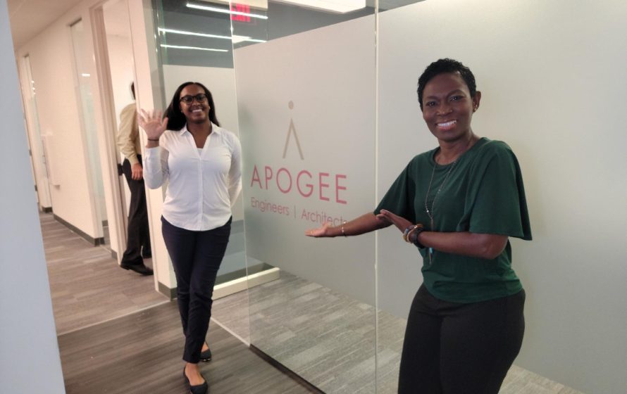 Two Apogee employees waving at camera in a hallway